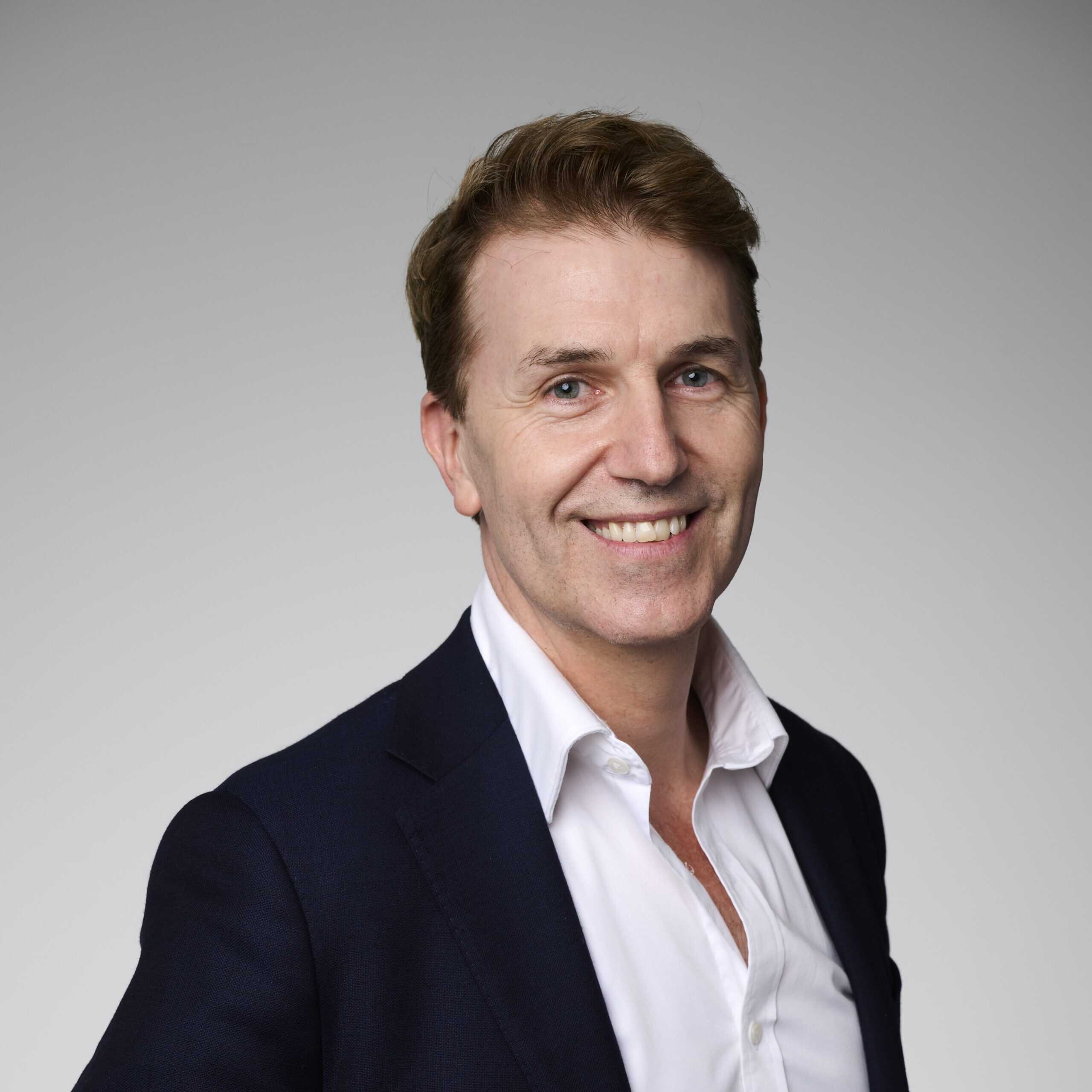 A corporate headshot of David Sly, smiling and wearing black and white clothing.