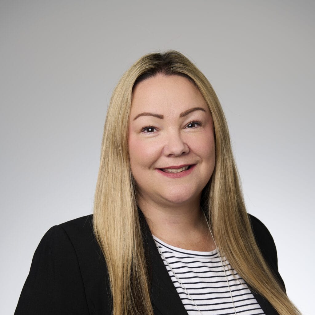 A corporate headshot of Jacci Williams, smiling and wearing black and white clothing.