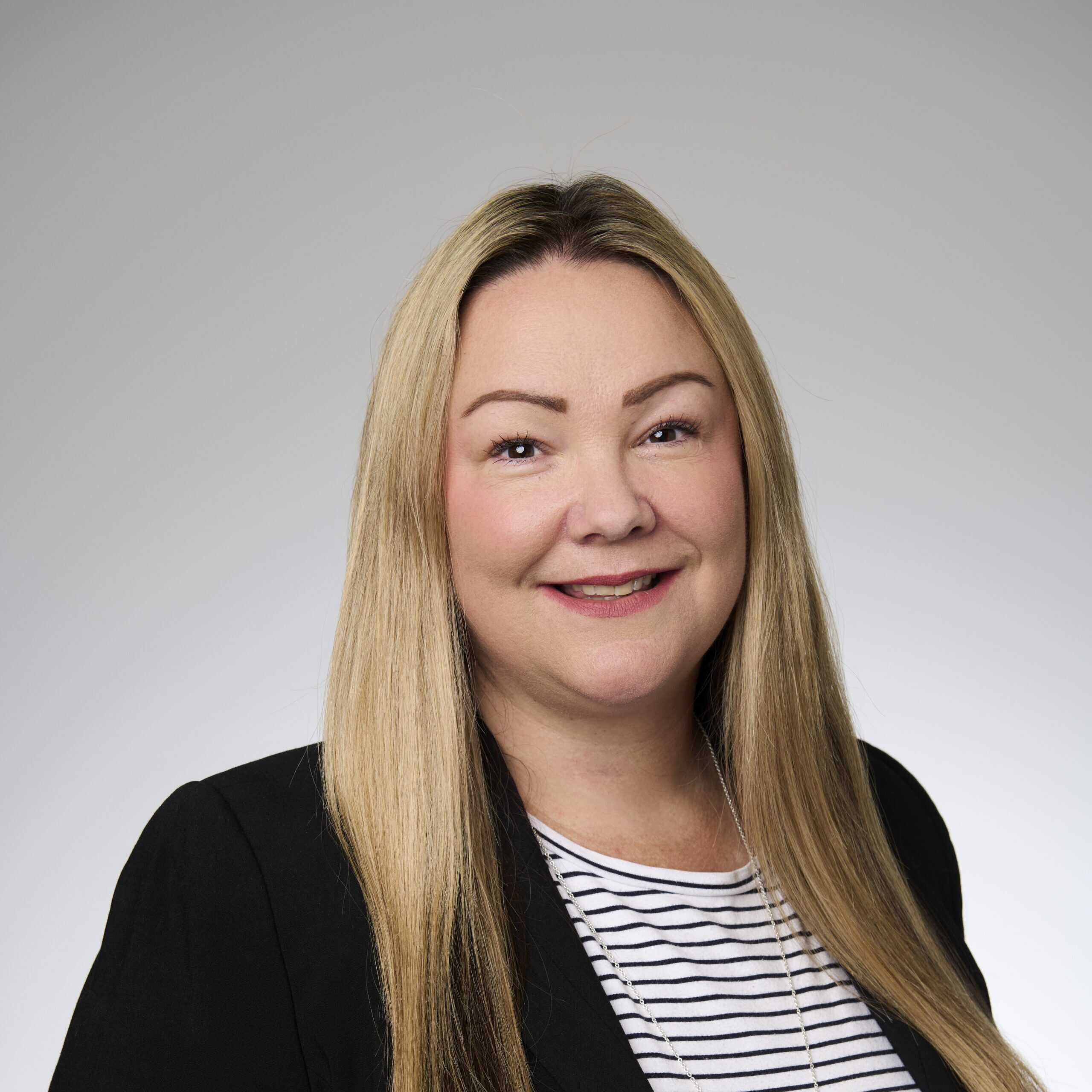 A corporate headshot of Jacci Williams, smiling and wearing black and white clothing.